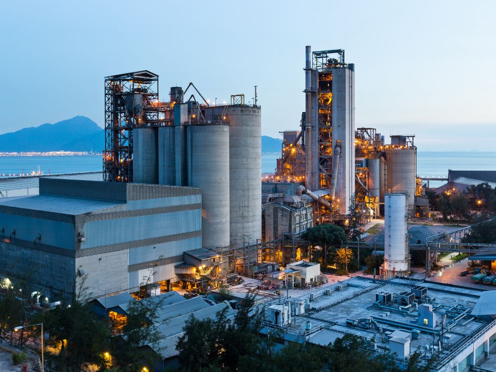 Vista panorâmica de uma indústria de base com grandes estruturas metálicas e tanques de produção, representando o setor industrial de base e sua importância econômica.