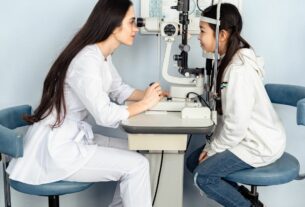 Oftalmologista realizando exame de vista em criança com equipamento de lâmpada de fenda em consultório especializado.