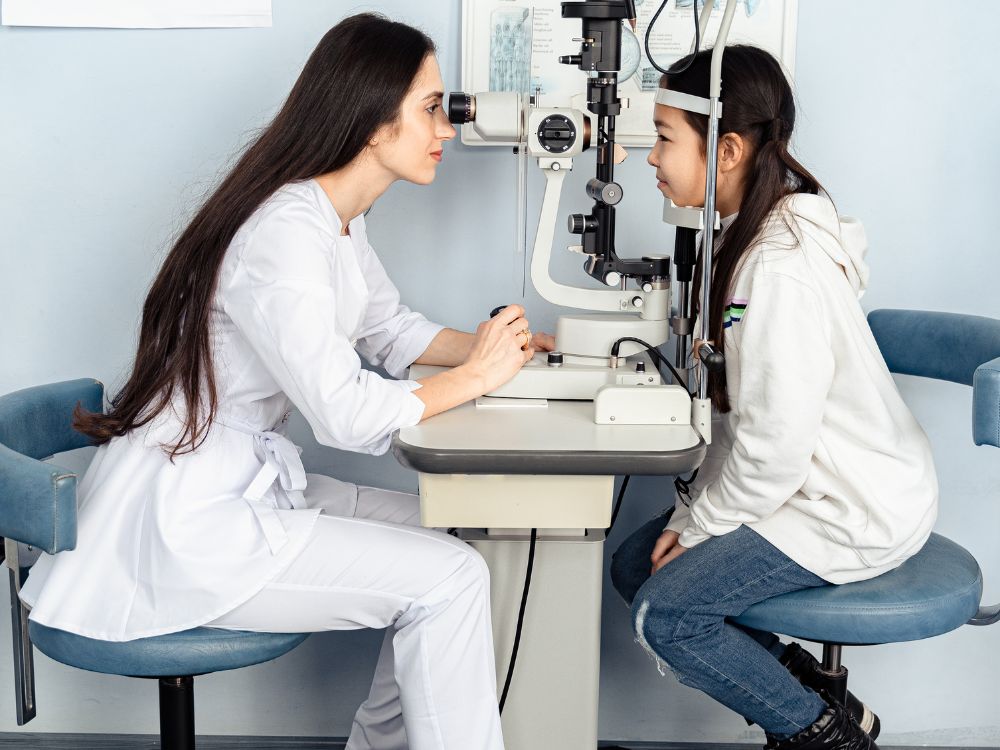 Oftalmologista realizando exame de vista em criança com equipamento de lâmpada de fenda em consultório especializado.