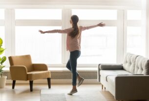 Pessoa em apartamento iluminado comemorando a conquista de morar sozinho, representando planejamento de mudança e dúvidas comuns como o que é uma kitnet ao escolher um imóvel para viver.