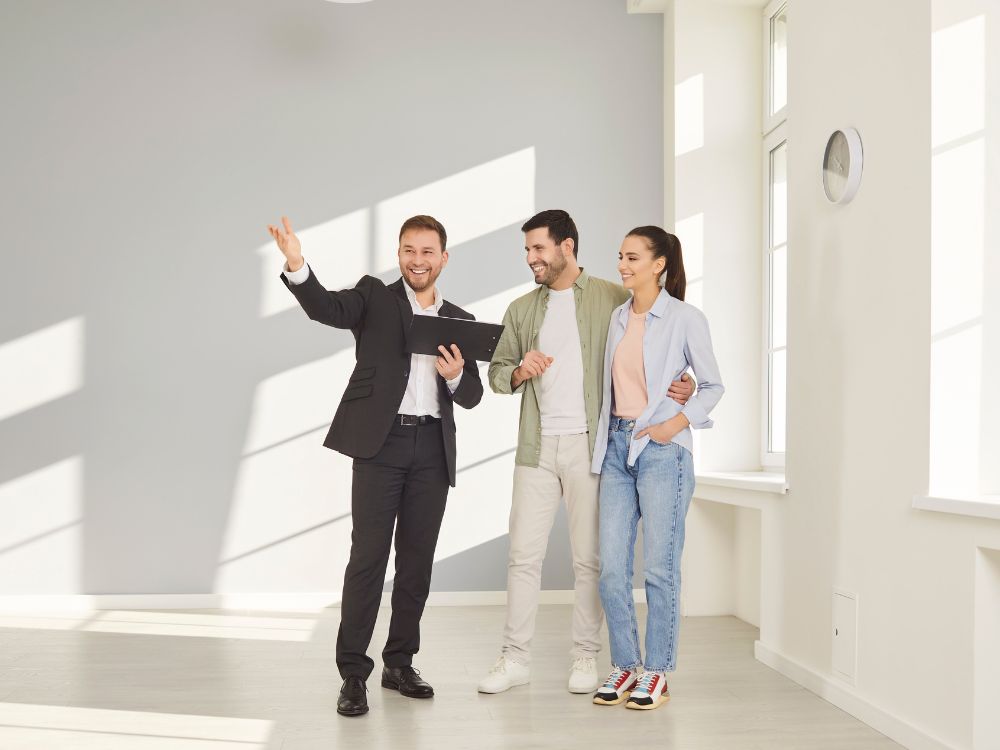 Corretor imobiliário apresentando um apartamento para casal durante visita ao imóvel, representando o processo de como escolher um apartamento para alugar e entender questões como seguro fiança é devolvido.