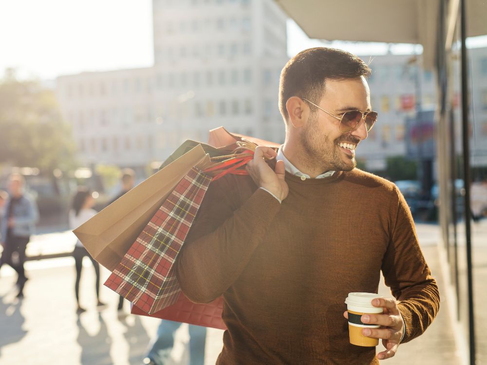 Homem carregando sacolas de compras em área urbana, representando opções variadas de compras em Santa Catarina em diferentes cidades e centros comerciais.